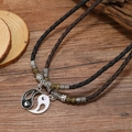 Yin Yang Tai Chi couple necklaces with hand-woven cord on vintage wooden surface - Two-Piece Set