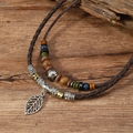 Retro leaf pendant necklace with woven cord and colorful wooden beads on wood background - Brown Cord Leaf Pendant