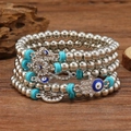 Luxurious Hamsa and Evil Eye multilayer beaded bracelet set on a rustic wood surface - Silver