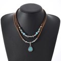 Détail d'un collier bohème à deux rangs avec pierres turquoise et accents en métal vieilli - Style Pendentif Turquoise en Forme de Larme