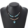 Détail d'un collier bohème double couche avec pendentif cœur turquoise sur mannequin noir - Style Pendentif Turquoise en Forme de Cœur