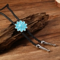 Detalle de corbata bolo de margarita azul con cordón trenzado negro y puntas metálicas plata - Flor