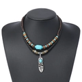 Détail d'un collier bohème à double rangée avec perles turquoise et pendentif plume argenté - Style de Plume en Métal Incrustée de Turquoise