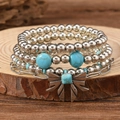 Detailed view of bohemian turquoise bead bracelets with vintage silver bow charm on wood - Style 09