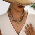 Detail van de bohemien gelaagde ketting met turquoise kralen en stierenkop hanger - 12 Koeienschedel Cowboyhoed Halsketting Set