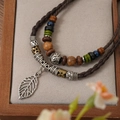 Close-up of multi-layer woven necklace with wooden beads and silver leaf pendant - Leaf Pendant Necklace