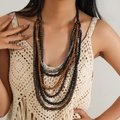 Détail d'un collier bohème multicouche avec perles en bois et turquoise sur un mannequin - Design patchwork gris-bleu (collier vintage : style 5)