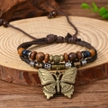 Macro detail of braided leather bracelet with wooden beads and bronze butterfly charm - Bracelet 18