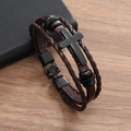 Dettaglio del bracciale in pelle multistrato con croce nera opaca su sfondo in legno - Pelle Marrone Croce