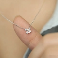 Close-up of sparkling four-leaf clover pendant with fine silver chain on hand - White Gold