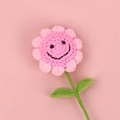 Handmade crochet sunflower in pink with smiling face detail on a soft pink background - Pink - 5-ring Smiley Face Sunflower Stem With 2 Leaves (40cm Flower Stalk)