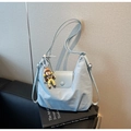Detail der hellblauen Hobo-Tasche mit verstellbarem Gurt und süßem Puppenanhänger - Blau mit Anhänger