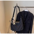 Details der schwarzen Nylon-Halbmondtasche mit Lederklappe und Perlen-Puppenanhänger - Schwarz mit Anhänger