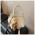 Detail of white textured leather crossbody bag with embossed logo and plush bear charm - White with Pendant