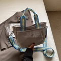 Graue Canvas-Tasche mit blau-gelbem breitem Schultergurt in einer Lifestyle-Szene - Grau