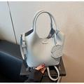 Detail of light blue lychee pattern leather tote bag with dog charm on black art books - Blue