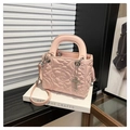 Macro detail van roze gewatteerde emmer tas met zilveren kruis hanger en fijne riem - Roze