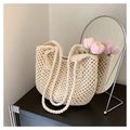 Detail of hand-woven cream tote bag with fringe charm and braided strap in a cozy interior - Off White