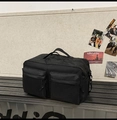 Vue détaillée du sac de voyage en nylon noir avec grandes poches avant sur un banc - Noir Pur