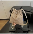 Beige Beuteltasche aus Nylon mit Kordelzug und verstellbarem Riemen auf schwarzem Sofa - Khaki