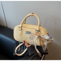 Detail der cremefarbenen gewebten Boston Tasche mit weißer Spitzenschleife und Logo - Mit Anhänger / Gelb