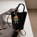 Chic black crocodile embossed bucket bag with cute cartoon charm on white linen - Black