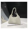 Detail einer beigen Ledertasche mit modischen silbernen Ösen und einem breiten Gurt - Kleine Öse / Weiß