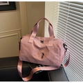 Roze multifunctionele nylon reistas met dubbele handgrepen en riem op een lederen stoel - Roze
