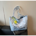 Detail of light blue canvas tote bag featuring floral pendant and striped lining on a sofa - Blue with Charm