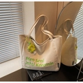 Detail of canvas tote bag with green embroidery and yellow flower charm in soft lighting - Beige With Charm