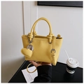 Detail van gele bucket bag met hartjeshanger en afneembare schouderriem van leer - Geel