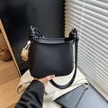 Chic black litchi leather bucket bag with knot handle and cartoon charm detail - Black