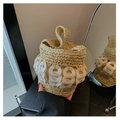 Close-up of handmade woven bucket bag featuring interlocking white ring details on handle - Beige