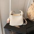 Cream white lychee leather bucket bag with cute rabbit pendant and knotted strap detail - Off White
