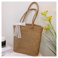 Close-up of woven straw beach bag with delicate white lace bow and hollow mesh pattern - Khaki