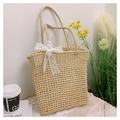Close-up of woven straw tote bag with white polka dot lace bow and diamond pattern - Off-white