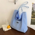 Hellblaue Canvas-Tragetasche mit BEAUT-Logo auf Holztisch in minimalistischem Stil - Blau