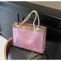 Detail of purple transparent PVC tote bag with gold trim and sturdy rope handles on a chair - One Size / Pink