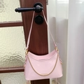 Detail showing pink patent leather hobo bag with gold chain hanging on a dark wood door - Pink