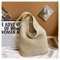 Detailed close-up of a cream woven straw tote bag featuring a magnetic snap closure design - Off-white