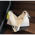 Minimalist white pleated shoulder bag with wide strap and yellow flower charm on stairs - Beige With Charm