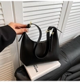 Minimalist black faux leather underarm bag with gold hardware on white books - Black