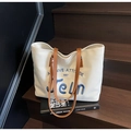 Close-up of cream canvas tote bag featuring blue embroidery and brown leather straps - Off-white