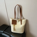 Beige woven straw tote bag with brown leather handles and decorative tassel ornament - White