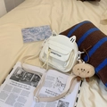 White cat-ear shoulder bag with letter print and brown plush charm on a cozy bed - White with Pendant