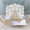 Close-up of laser-cut gold glitter wedding invitation with intricate bridal dress design - Light Gold Glitter