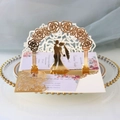 Macro view of 3D laser cut wedding invitation with golden rose arch and couple silhouette - Reflective Gold