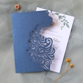Detail of laser-cut peacock wedding invitation with glitter finish and floral inner card - Magic Blue