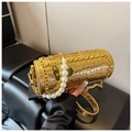 Dettaglio della borsa cilindrica oro con manico di perle e texture metallica - Oro