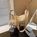 Chic beige dumpling bag featuring woven texture and cute plush cloud charm - White